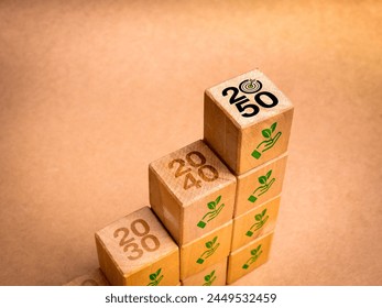 Net zero plan 2050. Reduce CO2 emissions reduction, limit climate change concept. 2050 years target icon on wood cube blocks growth graph steps with plant in hand symbol on recycle paper background.