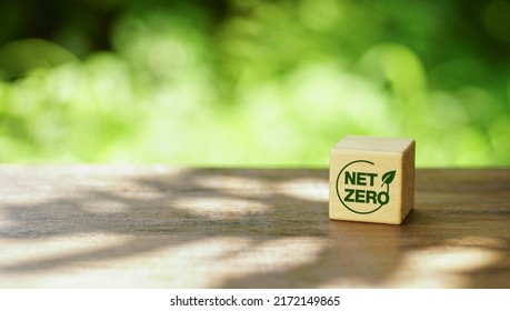 Net Zero Target And Carbon Neutral. Green Business Concept. Climate Changing Problems Solving Goals. Wooden Cubes With Net Zero Icon And Pollution Sources Icons On The Natural Background.             