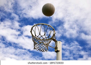 A Netball Ball Positioned High Above The Netball Goal.