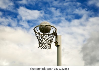 A Netball Ball Positioned Just Inside The Rim Showing An Impending Goal Is About To Be Scored.