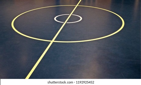 Netball And Basketball Centre Circle And Halfway Line Court Line Markings On An Indoor Court. Yellow And White Lines On A Blue And Black Floor.