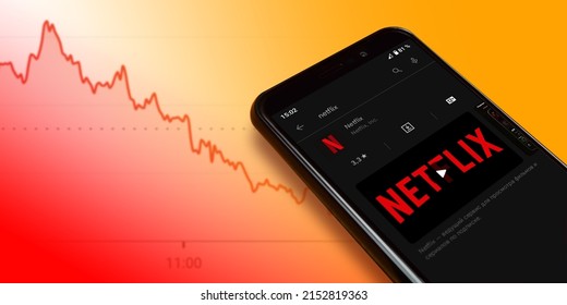 Netflix logo on smartphone screen with a chart of falling stock prices. Netflix streaming service for watching videos. Smartphone on orange background. Moscow, Russia - April 21, 2022.