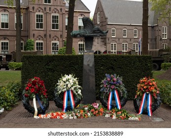 Netherlands - 4 may 2022, Laren: War Memorial with flower arrangements in the village Laren with parked military vehicles from the war in the background