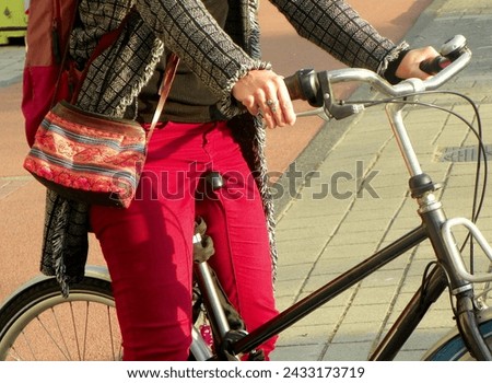 Netherlands, Amsterdam, Nieuwe Herengracht, woman in red pants on the bike