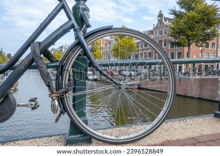 Netherlands. Autumn day in Amsterdam. The wheel of a bicycle parked on the bridge and the canal embankment
