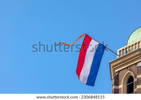 Netherlands flag with horizontal tricolour of red, white and blue, Orange flag hanging outside building, Celebration of the birthday of the King, National holiday King’s Day or Koningsdag in Dutch.