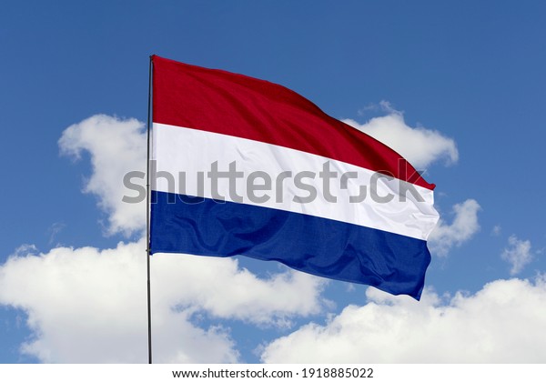 Netherlands flag isolated on the blue sky\
with clipping path. close up waving flag of Netherlands. flag\
symbols of\
Netherlands.