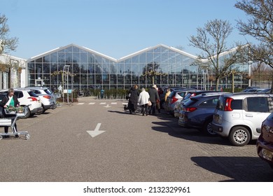 Netherlands, Heerhugowaard, March 4, 2022. Facade Dutch Garden Center Intratuin. People With Shopping Cart On The Parking Lot. Late Winter In The Sun.                               