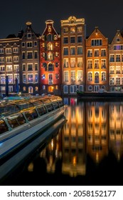 Netherlands. Night Amsterdam. Multi Colored windows of typical houses near the water and a pleasure boat