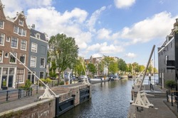 Netherlands. Old Ship Lock On The Amsterdam Canal. Typical Dutch Houses And Residential Barges On The Water