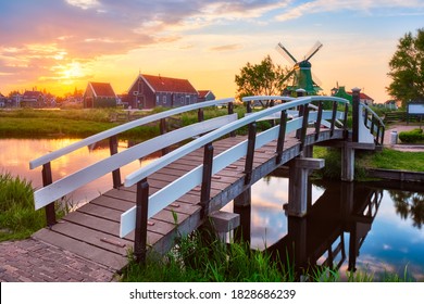 Netherlands rural scene - bridge over canal and windmills at famous tourist site Zaanse Schans in Holland on sunset with dramatic sky. Zaandam, Netherlands - Shutterstock ID 1828686239
