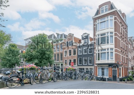 Netherlands. Summer day in Amsterdam. Light clouds in the blue sky. Several bicycles are parked near the railing of a bridge over a canal