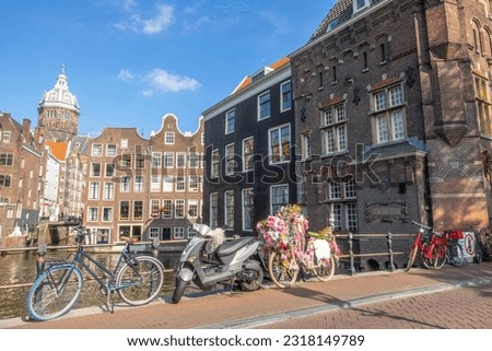 Netherlands. Summer day in Amsterdam. Scooter and bicycles near the railing of the bridge over the canal. Typical houses by the water
