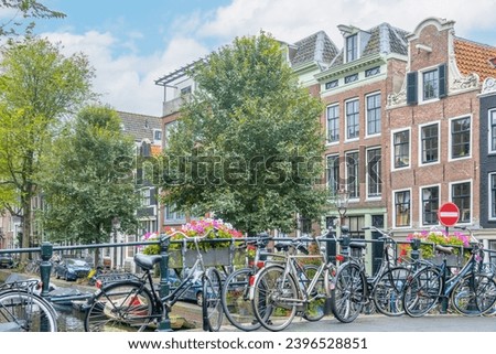 Netherlands. Summer day in Amsterdam. Several bicycles are parked near the railing of the flower bridge across the canal