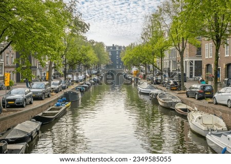 Netherlands. Summer day on the canal in the center of Amsterdam. Lots of moored boats. Lots of parked cars on the banks of the canal