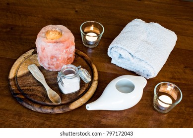 neti pot, ayurvedic system for cleaning nose with water and pink salt from Hymalaia, set with towel, pink hymalaian salt lamp and other candle, spoon and mason jar with salt