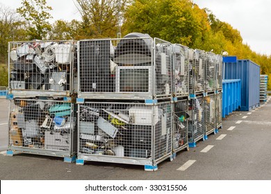 Netted bins full of discarded electronics waste waiting to be transported to the recycle plant for further processing. Blue containers in background.