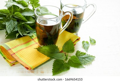 Nettle tea or decoction in glass cups and fresh urtica herb isolated on white wood, first spring vitamin green food and salad ingredient, closeup, copy empty space, healing herb concept - Shutterstock ID 1669654153