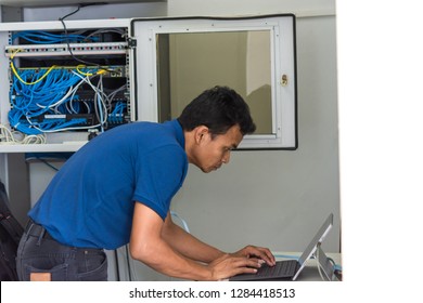Network administrator using laptop computer configuring switch on rack cabinet