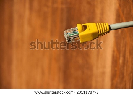 Network cable connector RJ45 close up view. LAN head cable macro view with wooden background.