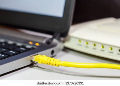 A network cable connects to the laptop, modem
