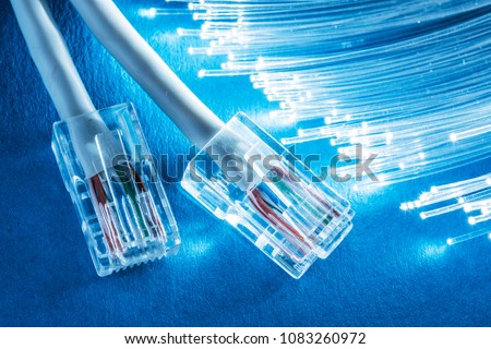 Network cables and bundle of optical fibers with lights in the ends. Blue background.