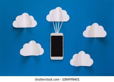 Network connection and cloud storage technology concept. Data communications and cloud computing network concept. Smart phone flying on paper cloud. Origami. Paper cut. Top view - Powered by Shutterstock - Get 15% off with code: PIKWIZARD15