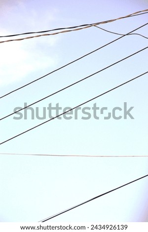 The network of electric cables with poles made of metal and clear sky in the morning as a background