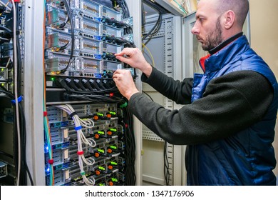Network engineer switches power cables in the server room rack. The system administrator works in the data center. Portrait of a technician working with computer equipment. - Shutterstock ID 1347176906