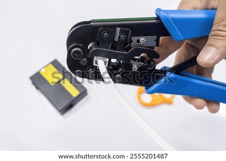 An IT network engineer using a crimping tool to attach an RJ45 connector to a network cable.