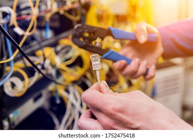 Network engineer working in server room. Connecting network cables to switches