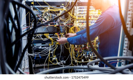 Network engineer working in server room. Connecting network cables to switches