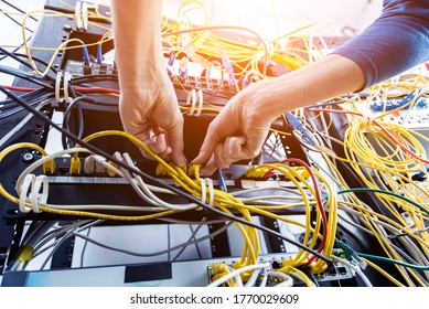 Network engineer working in server room. Connecting network cables to switches