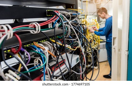 Network engineer working in server room. Connecting network cables to switches
