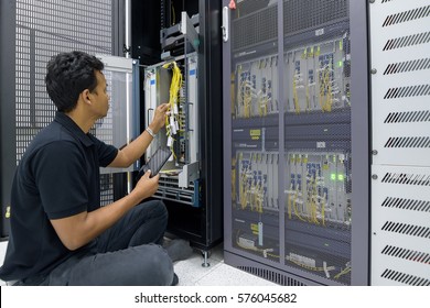 Network engineering administrator with tablet in hand working in datacenter.