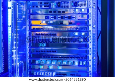 Network hardware. Dense Wavelength Division Multiplexing. Server system with transponders. Server cabinet in neon lighting. Fragment of switching equipment. Server multiplexing technology