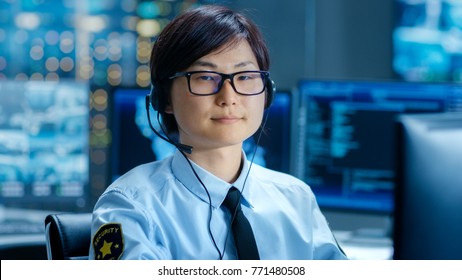 In The Network Operations Center Senior Trader Teaches Young Associate To Makes Personal Client Call With A Headset. They're Surrounded By Monitors Showing Data And Graphs.