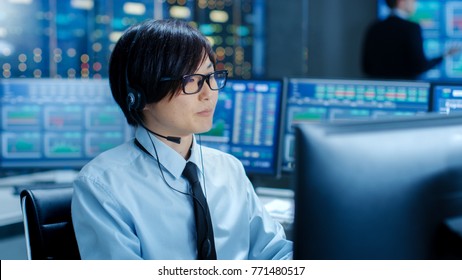 In The Network Operations Center Trader Makes Personal Client Call With A Headset. He's Surrounded By Monitors Showing Stocks Data And Graphs.