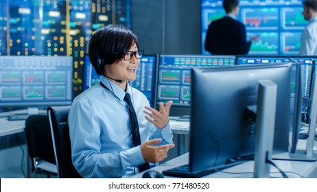 In The Network Operations Center Trader Makes Personal Client Call With A Headset. He's Surrounded By Monitors Showing Stocks Data And Graphs.