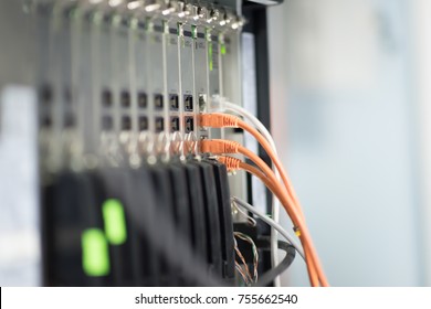 Network panel, switch and orange cable in data center.