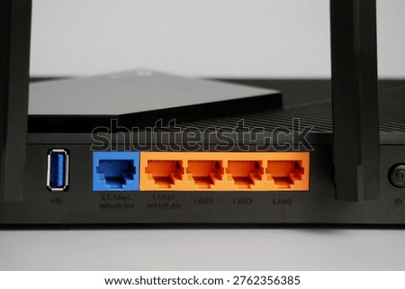 Network router rear panel with orange gigabit ethernet ports, blue wanlan port and usb connector, close up tech detail.