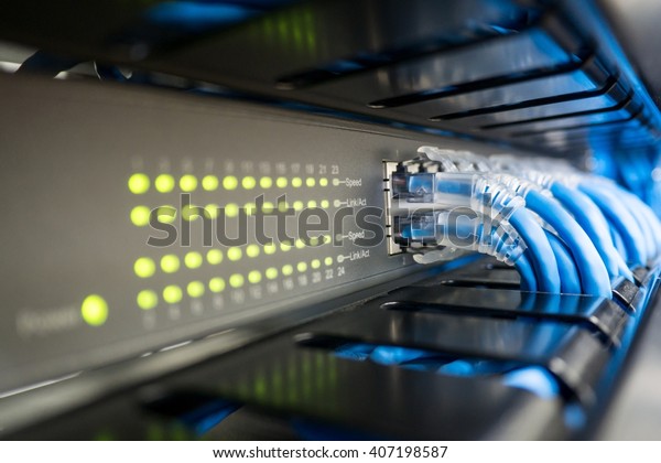 Network switch and ethernet cable in rack cabinet.\
Network connection technology and has a status LED to show working\
status. Concept of infrastructure with cables connected to data\
center