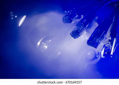 Network switch and ethernet cables, symbol of global communications. Colored network cables on dark background with lights and smoke. Selective focus. Network internet concept background