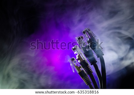 Network switch and ethernet cables, symbol of global communications. Colored network cables on dark background with lights and smoke. Selective focus. Network internet concept background