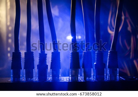 Network switch and ethernet cables, symbol of global communications. Colored network cables on dark background with lights and smoke. Selective focus. Network internet concept background