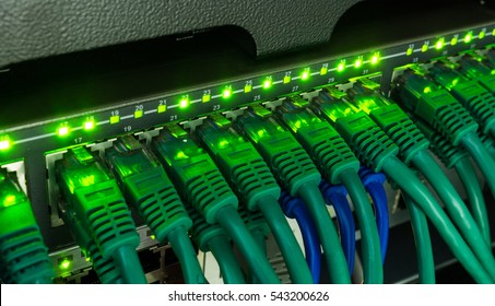 Network switch and green ethernet cables glowing in server room. Patch cords connected to router in data center. Horizontal technology background - Powered by Shutterstock