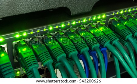 Network switch and green ethernet cables glowing in server room. Patch cords connected to router in data center. Horizontal technology background