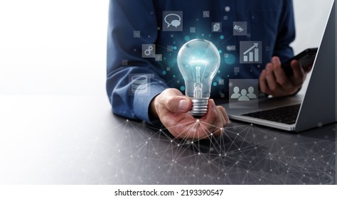 Network Technology And Business Solution Image.  Man Holding Lightbulb And Smartphone. Laptop And Computer Network.
