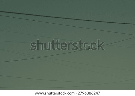 A network of thin, dark electrical wires crisscrosses a hazy, desaturated sky, creating a minimalist, graphic composition