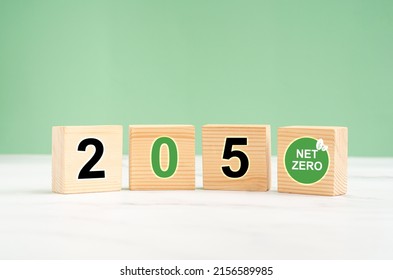 Net-zero greenhouse gas emissions in 2050 target. Climate-neutral long-term strategy. Wooden cubes with green icons against a light green background. Close-up photo. Space for text - Shutterstock ID 2156589985